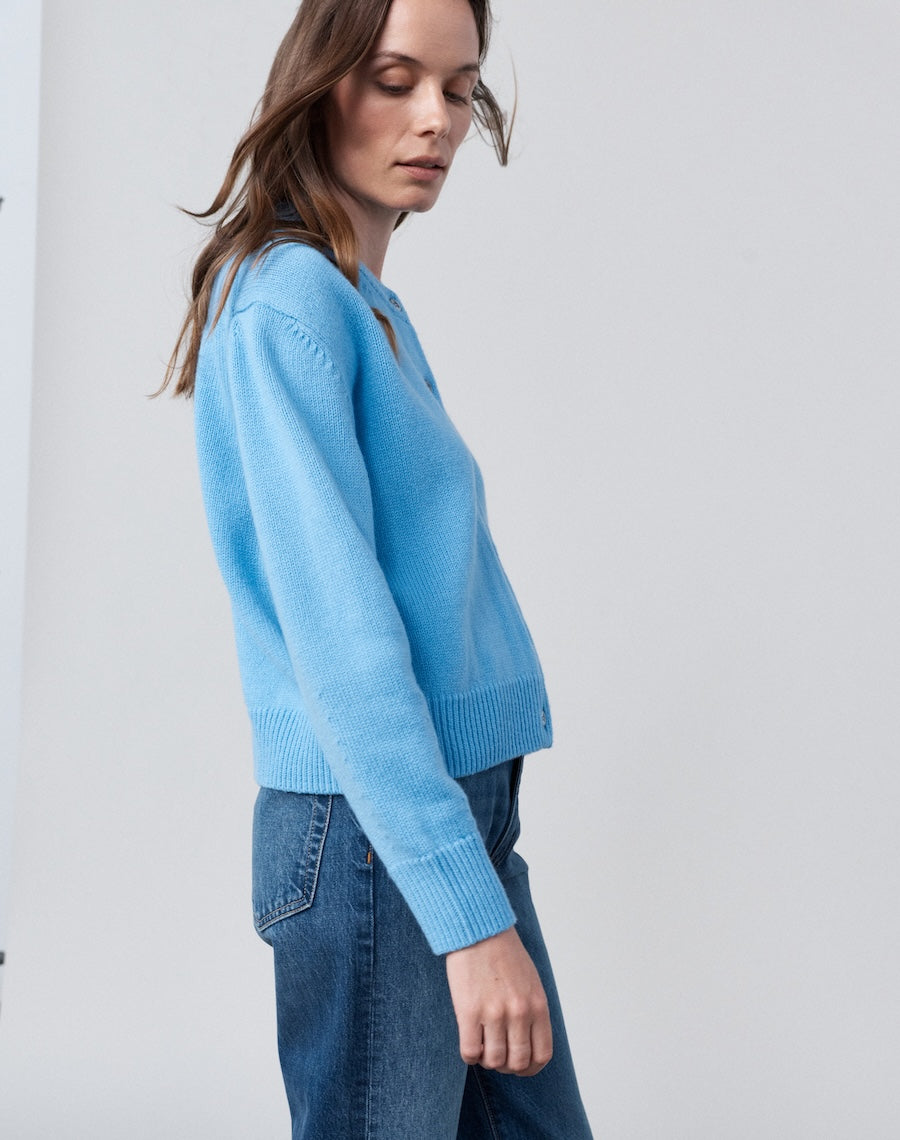 Woman wearing a light blue sweater and jeans against a white background