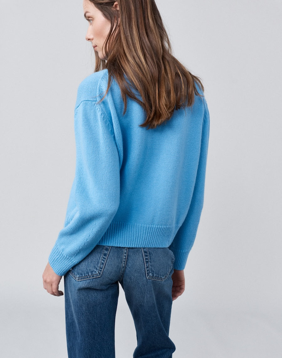 Person wearing a light blue sweater and jeans on a plain background